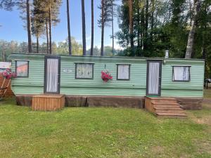 a green house with windows and flowers in a yard at Summer beach house in Saulkrasti +16 photos