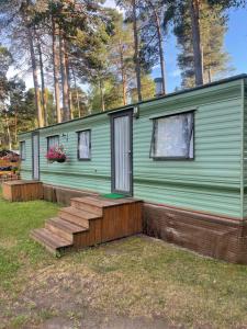 a green tiny house with a porch and stairs at Summer beach house in Saulkrasti