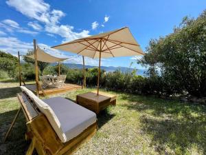 ein Bett und ein Regenschirm im Gras in der Unterkunft Maison en bord de mer in Coggia