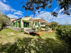 ein Haus mit einer Terrasse und einem Sonnenschirm in der Unterkunft Maison en bord de mer in Coggia