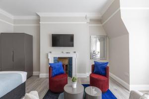 1 dormitorio con 1 cama y 2 sillas rojas en Air Conditioned Apt High St Kensington en Londres