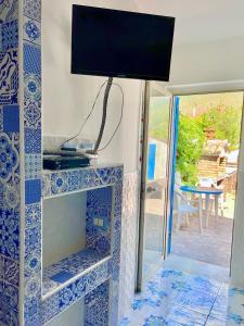 a tv on top of a blue and white tiled fireplace at AMALFI ROOM ~ Camera indipendente con Bagno interno per Max 3/4 Persone in Palinuro