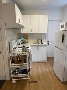 Private Single Room with Shared Bathroom 536C في تورونتو: مطبخ فيه دواليب بيضاء وثلاجة بيضاء