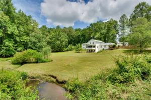 a house on a large yard with a pond at Georgia Vacation Rental with Covered Deck and Patio in Dahlonega