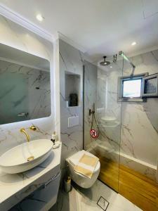 a bathroom with a sink and a toilet and a shower at Allea Hotel and Apartments in Toroni