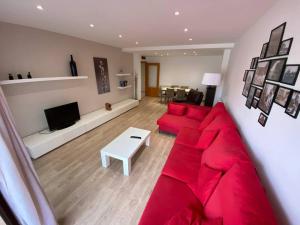 a living room with a red couch and a tv at Piso céntrico recién reformado in Torredembarra