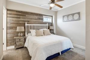 a bedroom with a white bed and a wooden accent wall at FFR101 - The Wright Idea in Kill Devil Hills