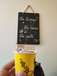 una mano che tiene una tazza di caffè con un cartello di B&B GIOIA a Catanzaro
