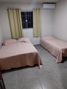 2 camas en una habitación con ventana en Residencial Casa Grande - Apto 02, en Santa Cruz Cabrália