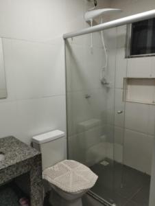 a bathroom with a toilet and a glass shower at Residencial Casa Grande - Apto 02 in Santa Cruz Cabrália