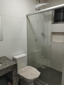 y baño con aseo y ducha acristalada. en Residencial Casa Grande - Apto 02, en Santa Cruz Cabrália