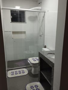 a bathroom with a toilet and a glass shower at Residencial Casa Grande - Apto 02 in Santa Cruz Cabrália