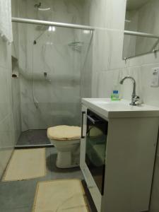 y baño con ducha, aseo y lavamanos. en Residencial Casa Grande - Apto 02, en Santa Cruz Cabrália