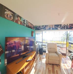 uma sala de estar com uma televisão grande e uma cadeira branca em Departamento Vista al mar 958 em Valparaíso