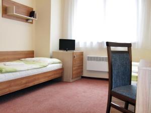 1 dormitorio con 1 cama, 1 silla y TV en Rekreačné zariadenie Crocus en Vysoké Tatry