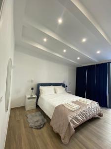 1 dormitorio con 1 cama blanca grande y cortinas azules en Cinque Terre Memory Affittacamere, en La Spezia