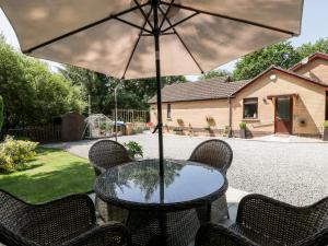 a table with chairs and an umbrella on a patio at Swn Y Nant in Tondu