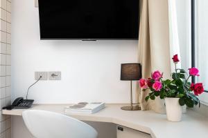 un escritorio blanco con TV y flores. en Hotel Carlo Felice, en Sassari