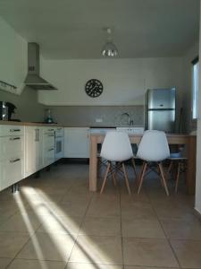 uma cozinha com duas cadeiras brancas e uma mesa em Maison au calme en campagne em Velleron