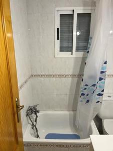 a bathroom with a tub with a shower curtain at Casa Denise in Playa de Gandia