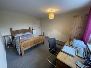 a bedroom with a bed and a desk with a computer at Manor Farm Holiday Cottages in Chard