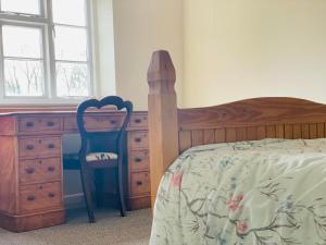 Schlafzimmer mit einem Bett, einem Schreibtisch und einem Stuhl in der Unterkunft Manor Farm Holiday Cottages in Chard