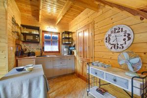 a kitchen with wooden walls and a clock on the wall at Domki Pod Brzozami in Dźwirzyno