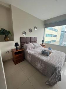 ein Schlafzimmer mit einem Bett und einem großen Fenster in der Unterkunft Chocolate suite! Wifi, Pool, gym, parqueo in Guayaquil