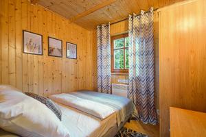 ein Schlafzimmer mit einem Bett in einer Holzhütte in der Unterkunft Domki Pod Brzozami in Dźwirzyno