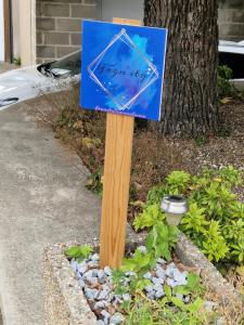 ein blaues Schild an einem Holzpfahl in einem Garten in der Unterkunft Fagn'ity in Weismes