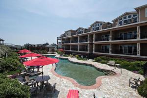 a hotel with a swimming pool with tables and umbrellas at CSC3H Rum Runner in Kill Devil Hills