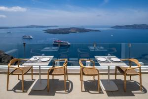 フィロステファニにあるIra Hotel & Spa - Adults Onlyのテーブルと椅子、水辺の景色を望むバルコニー
