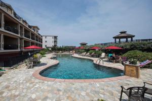 a swimming pool with chairs and umbrellas at a hotel at CSC4E-High Roller in Kill Devil Hills