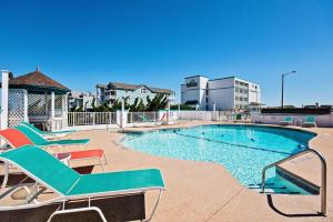 a swimming pool with chaise lounge chairs next to a building at CR102 - Sea 'n Ski in Kill Devil Hills
