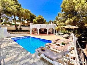 a swimming pool with chaise lounge chairs and a house at VH CostaBlanca - CARMEN in Teulada