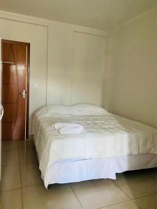a white bed in a room with a wooden door at Hotel Santorine Prime - Próximo a Fundação Cultural Carlos Drummond Andrade in Itabira
