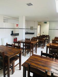an empty classroom with wooden tables and chairs at Hotel Santorine Prime - Próximo a Fundação Cultural Carlos Drummond Andrade in Itabira