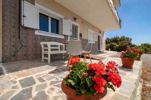 a patio with red flowers and a table and chairs at Laconian Collection # Gytheio Sea View Georgia Apartment# in Gythio