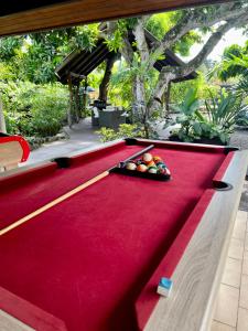 - une table de billard en feutre rouge avec un plateau de fruits dans l'établissement Heitiare lodge, à Paea