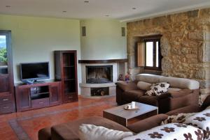 una sala de estar con sofás y una pared de piedra. en Casa rural con piscina 
