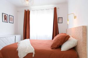 - une chambre avec un lit doté de draps orange et une fenêtre dans l'établissement Maison de village rénovée à 10 minutes des plages, à Saint-Laurent-de-la-Salanque