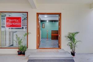 drzwi do hotelu z dwoma roślinami przed nim w obiekcie Capital O Royal Manyata w mieście Bengaluru