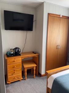 a bedroom with a desk and a tv on the wall at Impala Guest House in Wick +42 photos