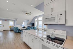 a kitchen with white cabinets and a living room at Sunrises to Sunsets in Nags Head