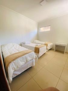 a bedroom with two beds and a tiled floor at Hotel Santorine Prime - Próximo a Fundação Cultural Carlos Drummond Andrade in Itabira