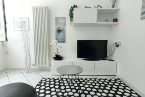 sala de estar blanca con TV y silla en Casa Lety con giardino, aria condizionata e wifi, en Rímini