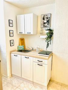 una cocina con armarios blancos y fregadero en Studio am Waldbach en Gernsbach