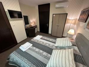 um quarto de hotel com duas camas e uma secretária em Хотел АВРОРА em Haskovo