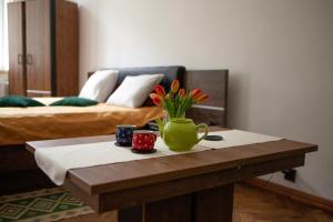 - une table basse avec un vase vert et des fleurs dans l'établissement Bailey Apartment, à Cracovie