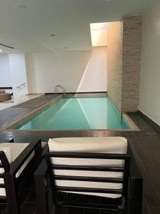 een zwembad met 2 stoelen en een tafel bij Coffee Suite, wifi, Parqueo, gym & piscina! in Guayaquil
